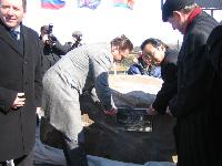 Ceremony participants in action to fix a memorial plate to a stone.