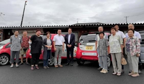 コミュニティ・カーシェアリングへのタイヤ寄贈セレモニーに参加した日本カーシェアリング協会の吉澤武彦代表理事（中央左）、横浜ゴムの森智朗CSR本部長代理（中央）とコミュニティ・カーシェアリングを利用する石巻市の皆様