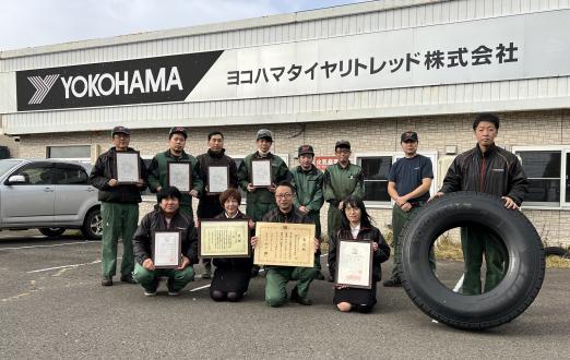 表彰状や認定証を手にするヨコハマタイヤリトレッド北海道事業所の社員。タイヤは同事業所で生産販売しているリトレッドタイヤ ※11月25日に写真を追加掲載しました。