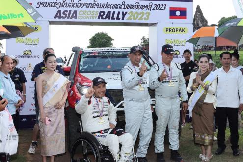Driver Takuma Aoki (center left) and co-drivers Ittipon Simaraks (center) and Songwut Danphiphattrankoon (center right), raising their arms in front of Toyota Fortuner SUV (#105) after winning the overall championship